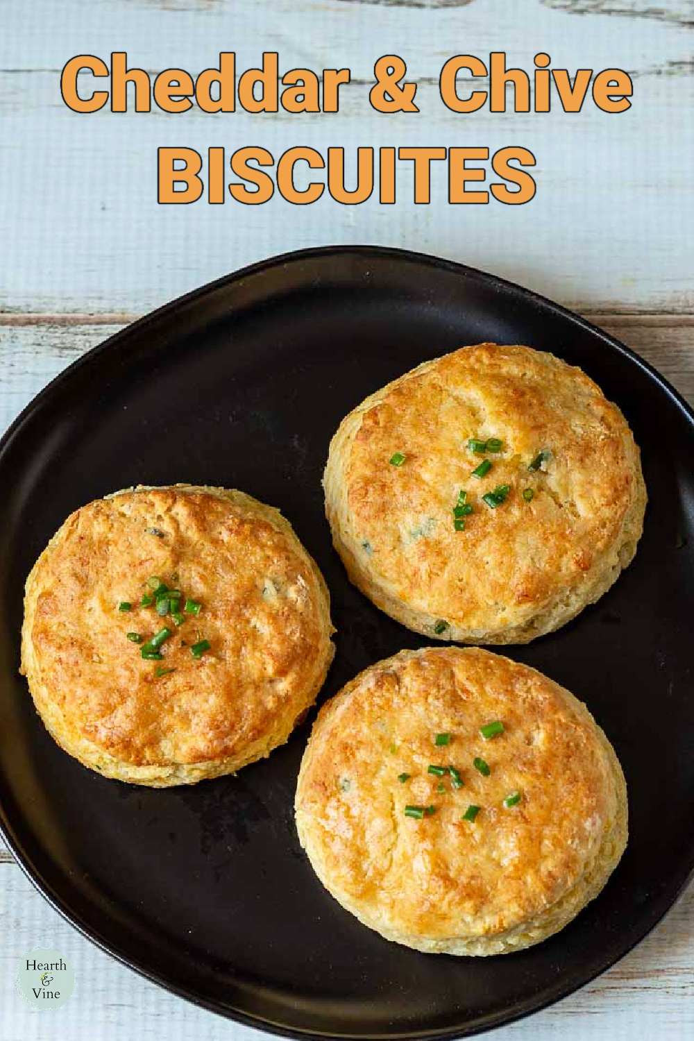 Three cheddar and chive biscuits on a plate.