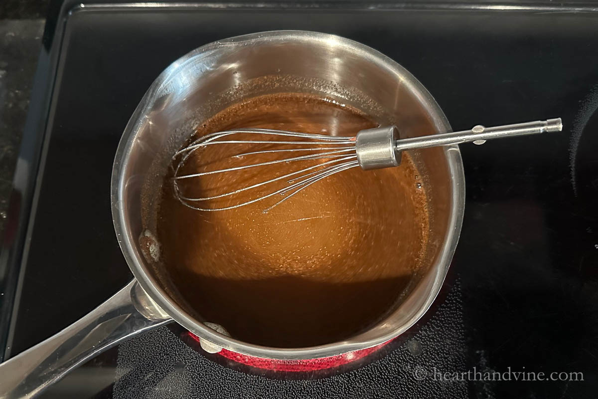 Cinnamon simple syrup in a saucepan with a wire whisk.