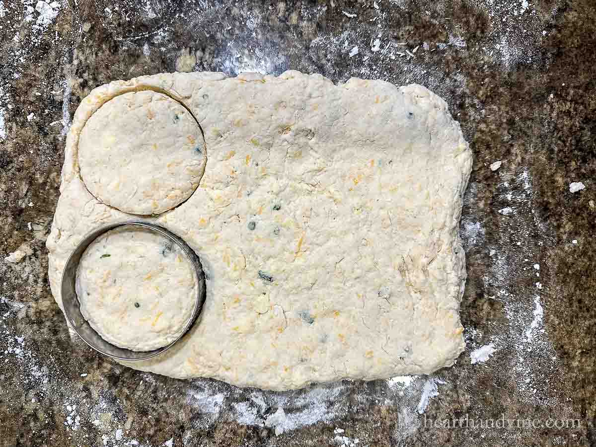 A round metal biscuit cutter cutting into dough.