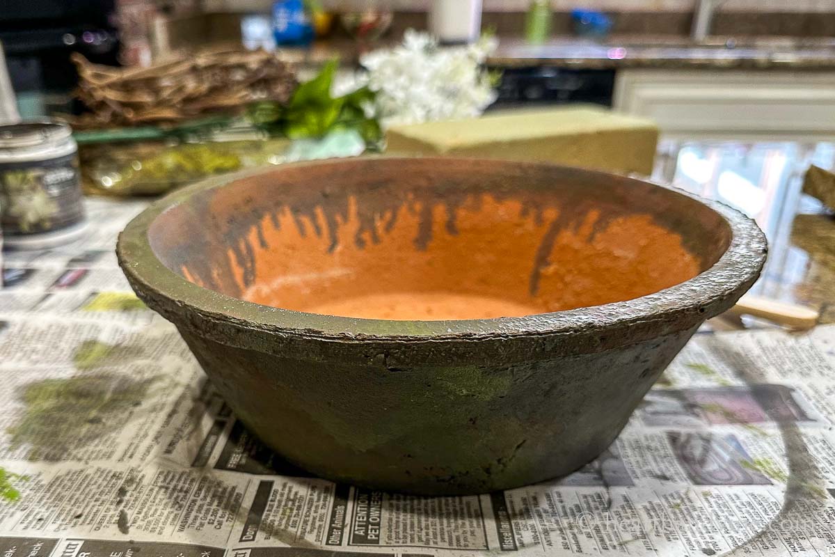 A shallow clay pot painted with gray and green shades of craft paint.