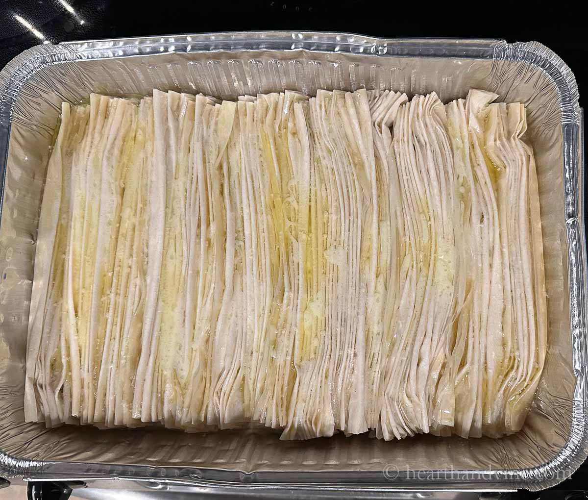 Folded phyllo in a pan with melted butter.