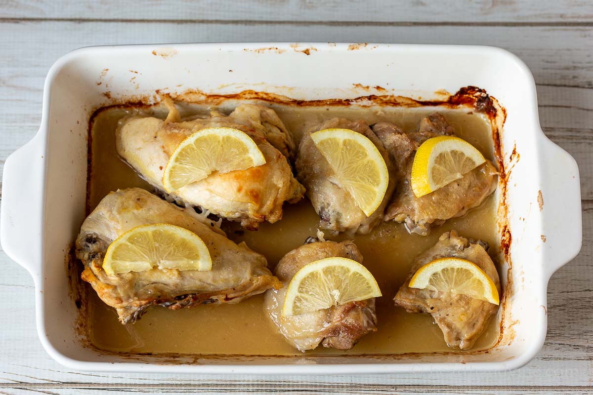 Cooked lemon chicken pieces with fresh slices of lemon on top of each piece.