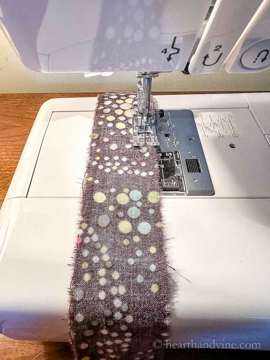 Fabric being sewn on a sewing machine.