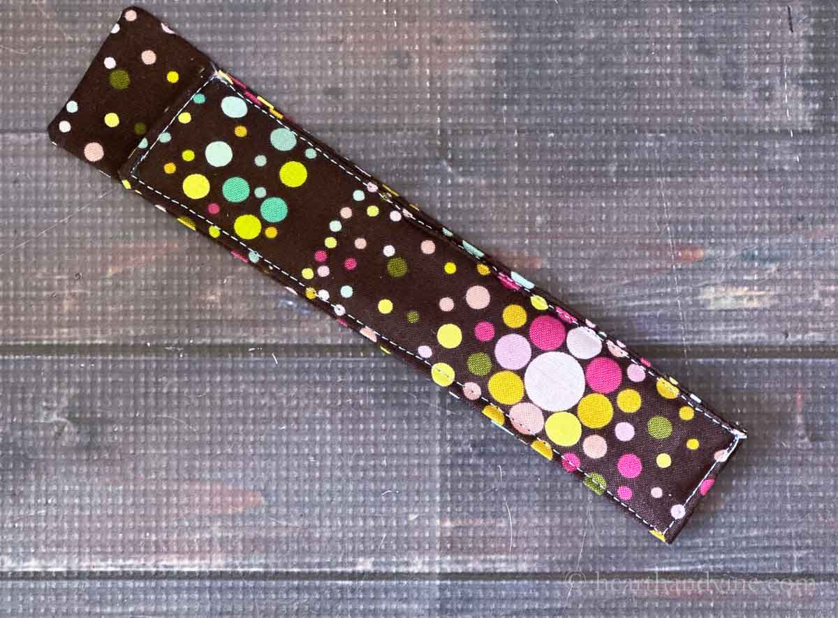 Finished nail file holder in brown and multi-colored fabric.