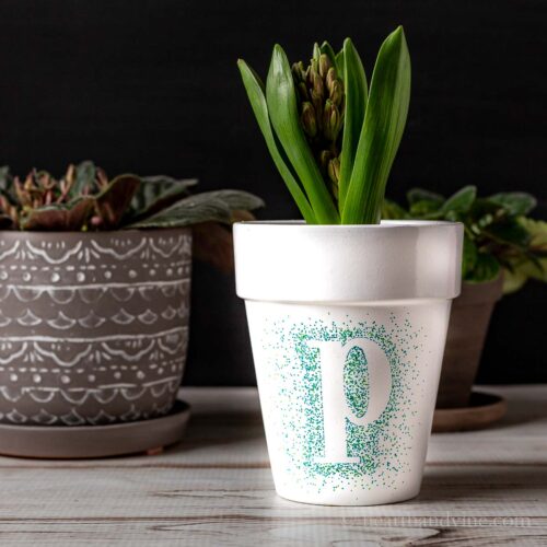 Monogrammed letter P on a white flower pot with dots of blue and green around it.