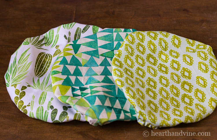 Three patterned cotton fabric bowl covers in shades of blue and green.