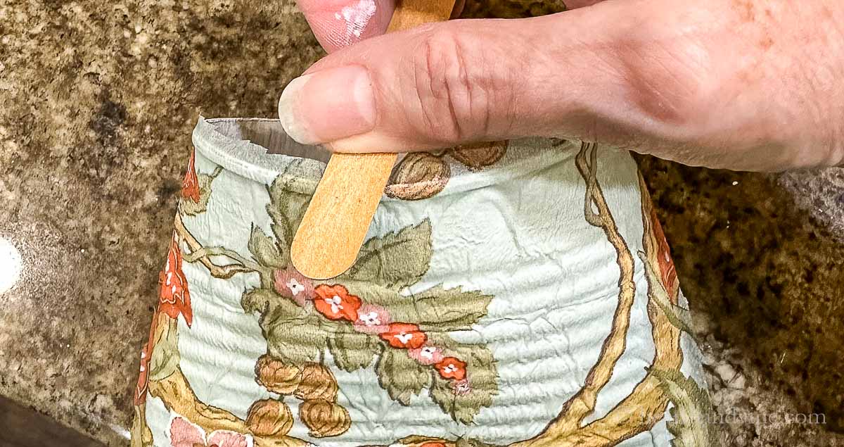 Using a nail file to remove excess paper napkin.