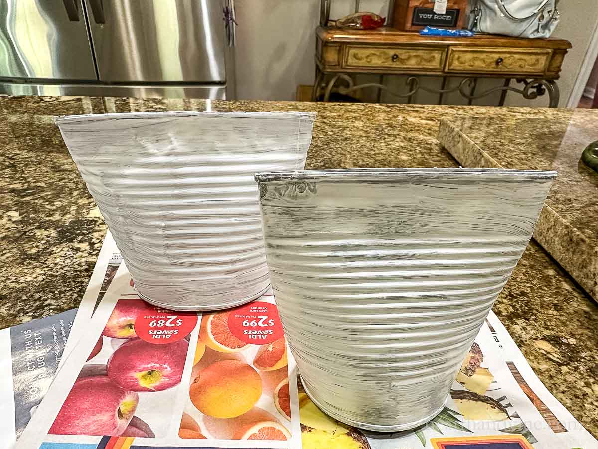 Two smashed tin cans with one coat of white craft paint.