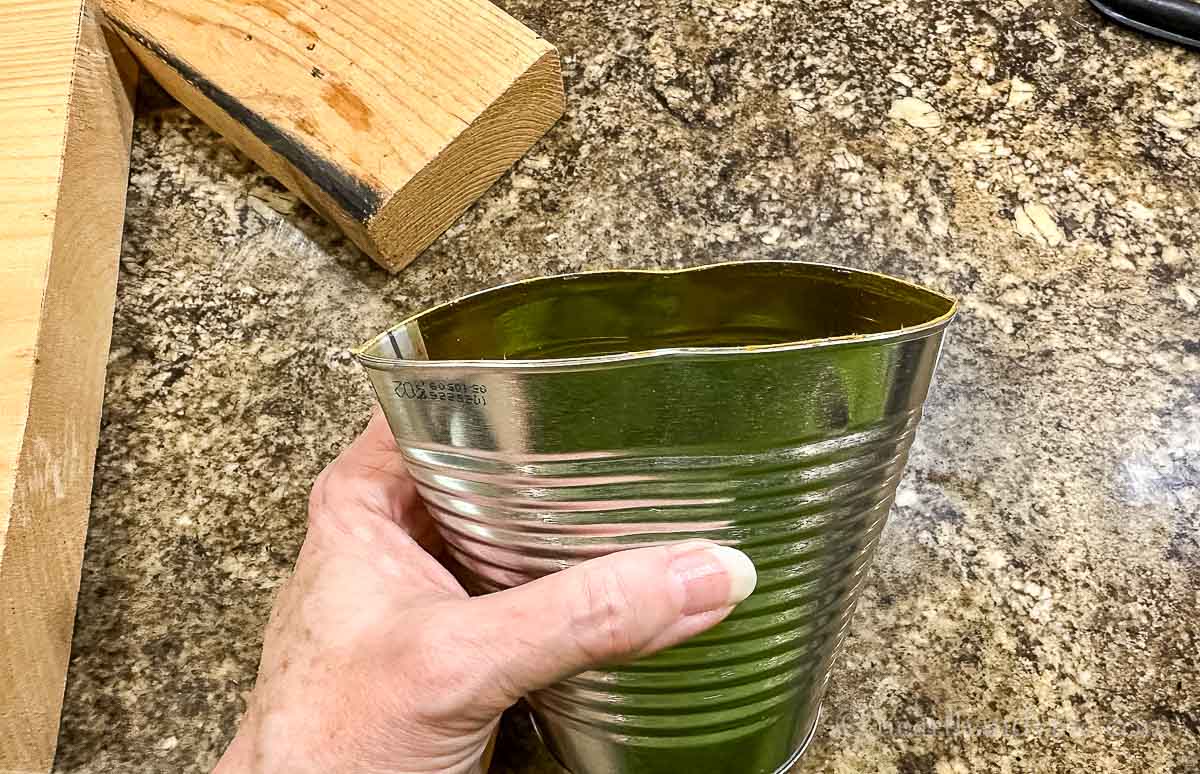 A hand squeezing a tin can at the bottom.