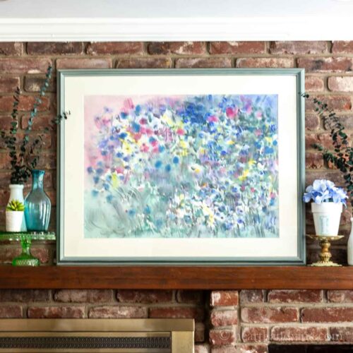 Center of summer decorated mantel with a large painting glass bottles and white vases.