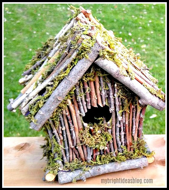 Birdhouse decorated with twigs and moss.