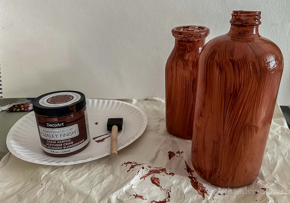 Two bottles with one coat of brown chalk paint.