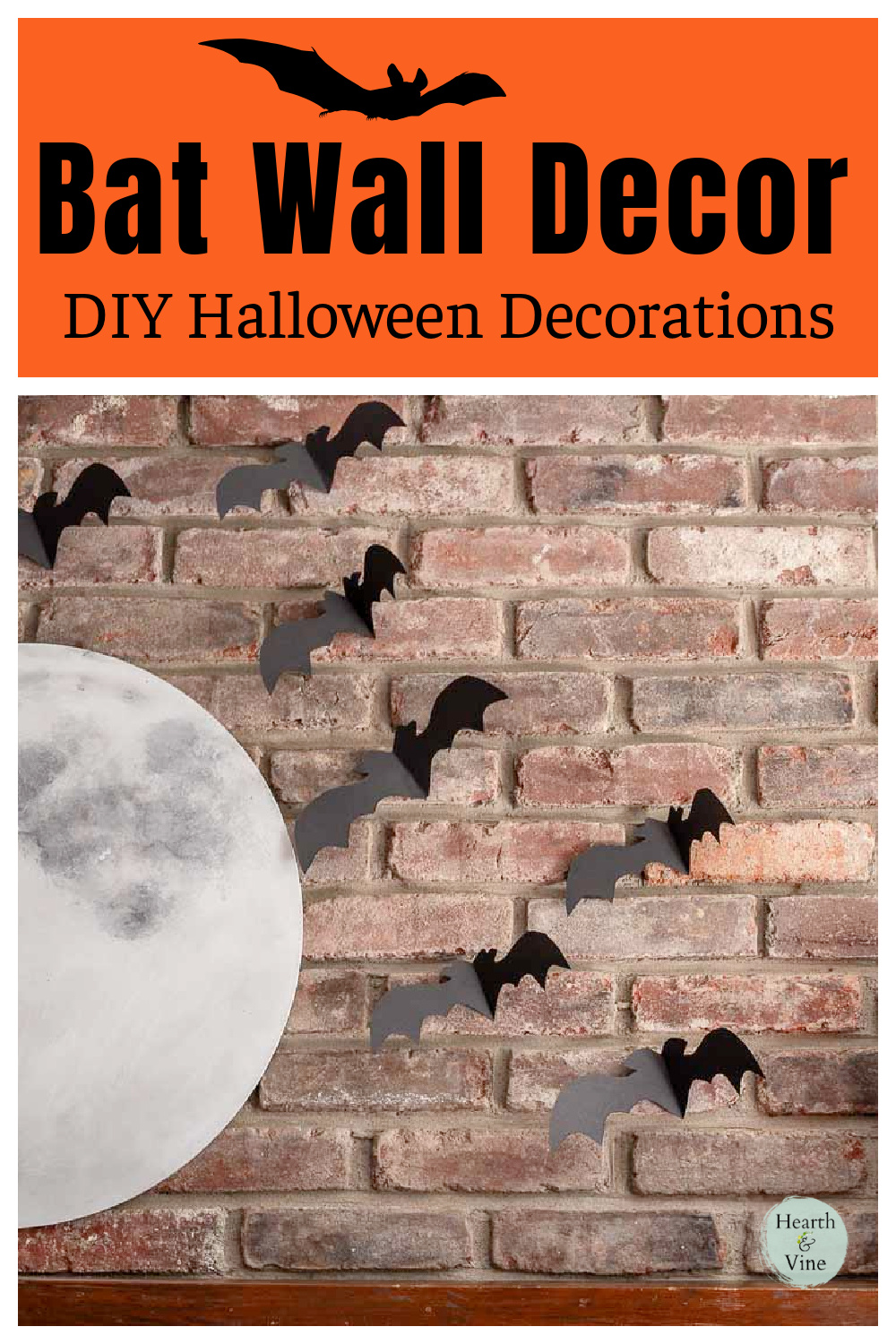 Partial view of a large full moon on a brick wall above a mantel with black paper bat flying on the side.