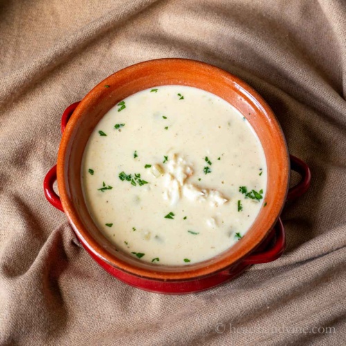 Serving of cream of crab soup in a red bowl.