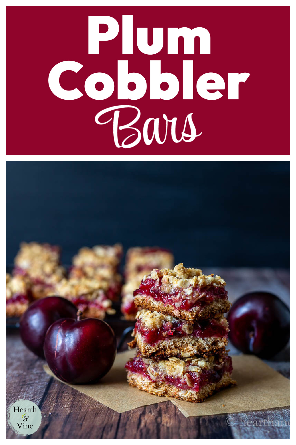 A stack of plum cobbler bars on parchment next to some fresh red plums.