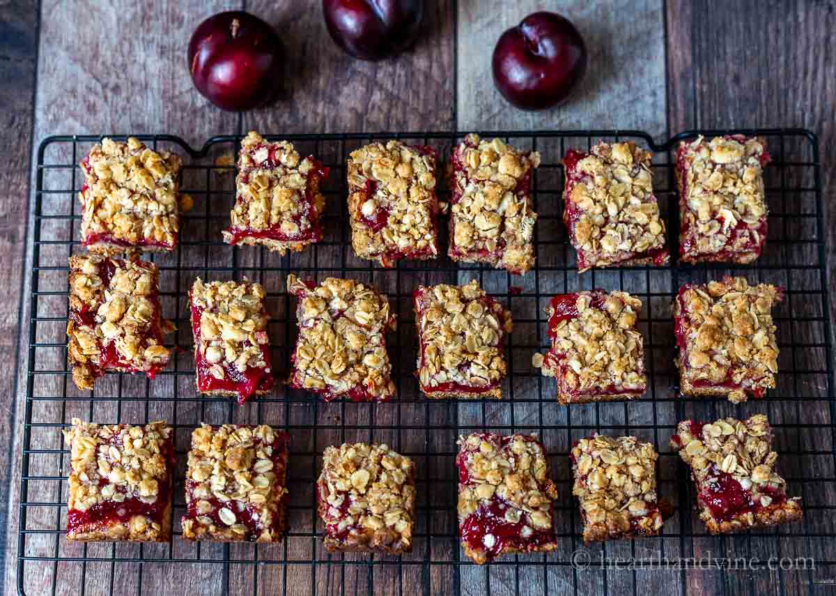 Plum crumble bars cooling on a wire rack and a few fresh plums on the side.
