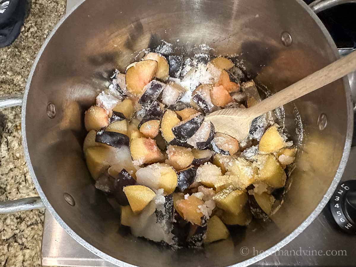 Chopped up plums and granulated sugar in a large pot.