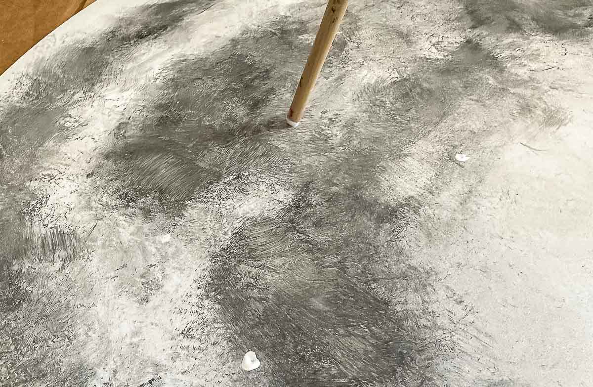 Using the end of a paintbrush to dab on dots of white on to the full moon painting.