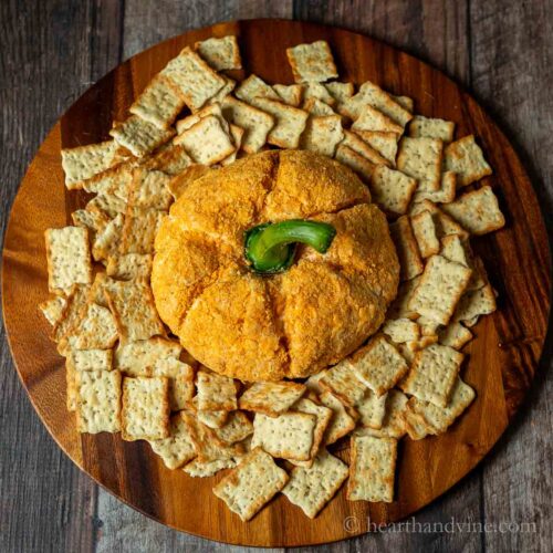 Pumpkin shaped cheese ball surrounded by crackers.