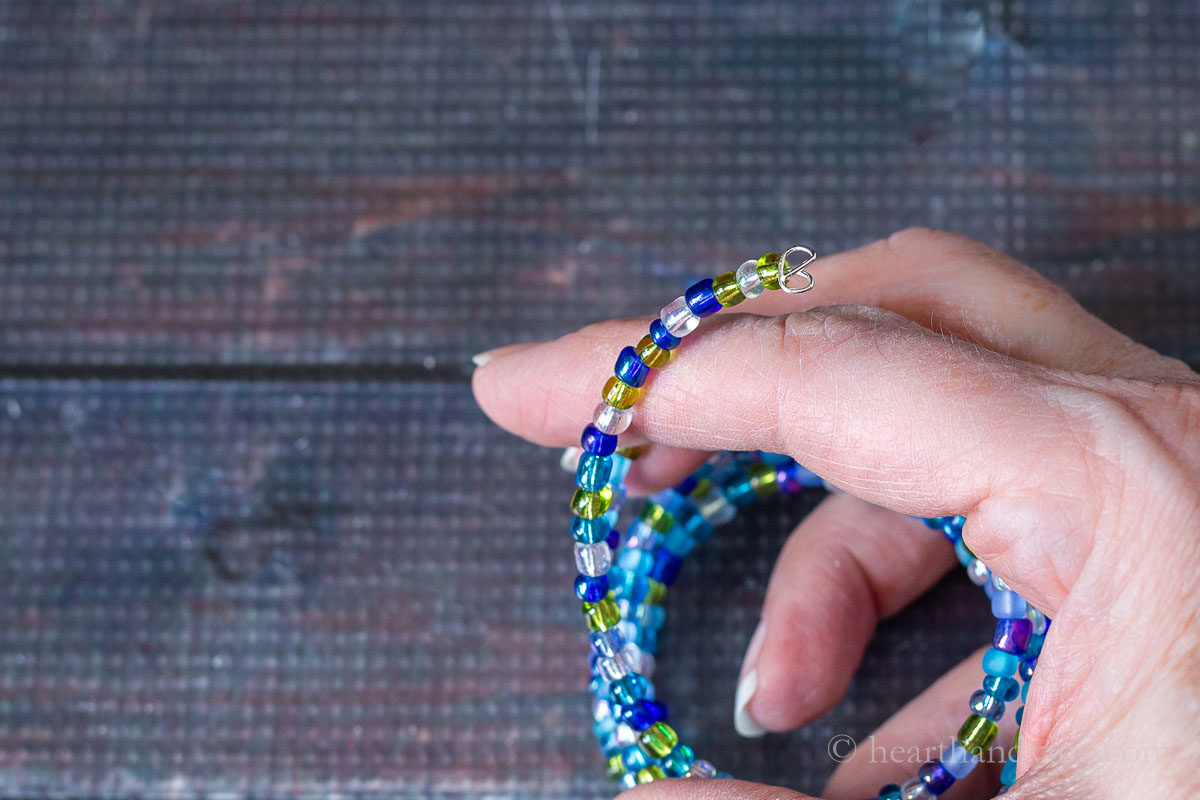 A hand holding the end of a multi-strand memory wire bracelet showing the wire enclosure.