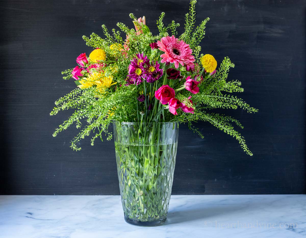 A variety of flowers in a large clear vase.