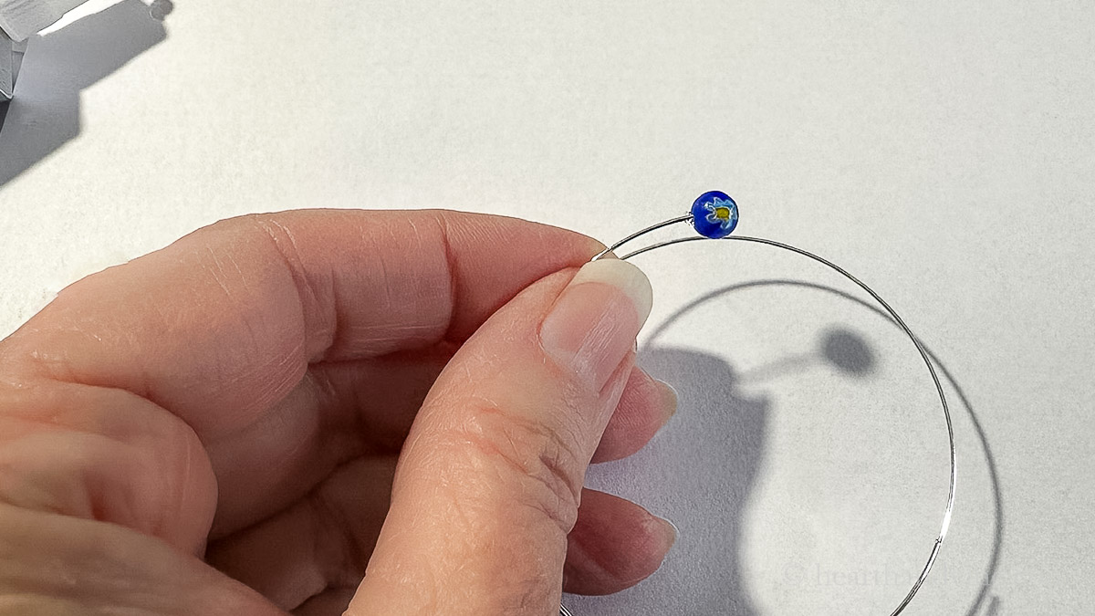 Small bead being glued on to the end of some memory wire.