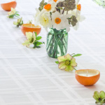 Table with orange candles and flower down the middle a vase with daffodils in the center.