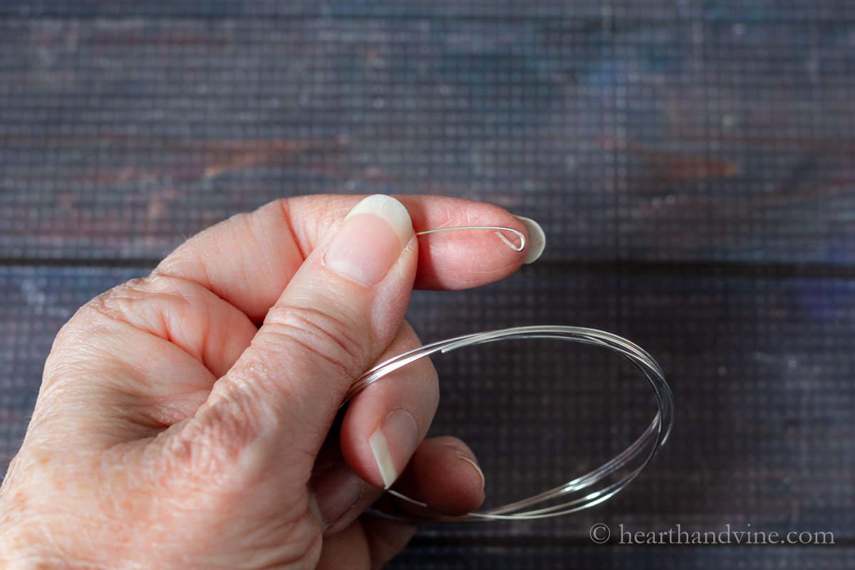 A hand holding one end of memory wire made into a loop.