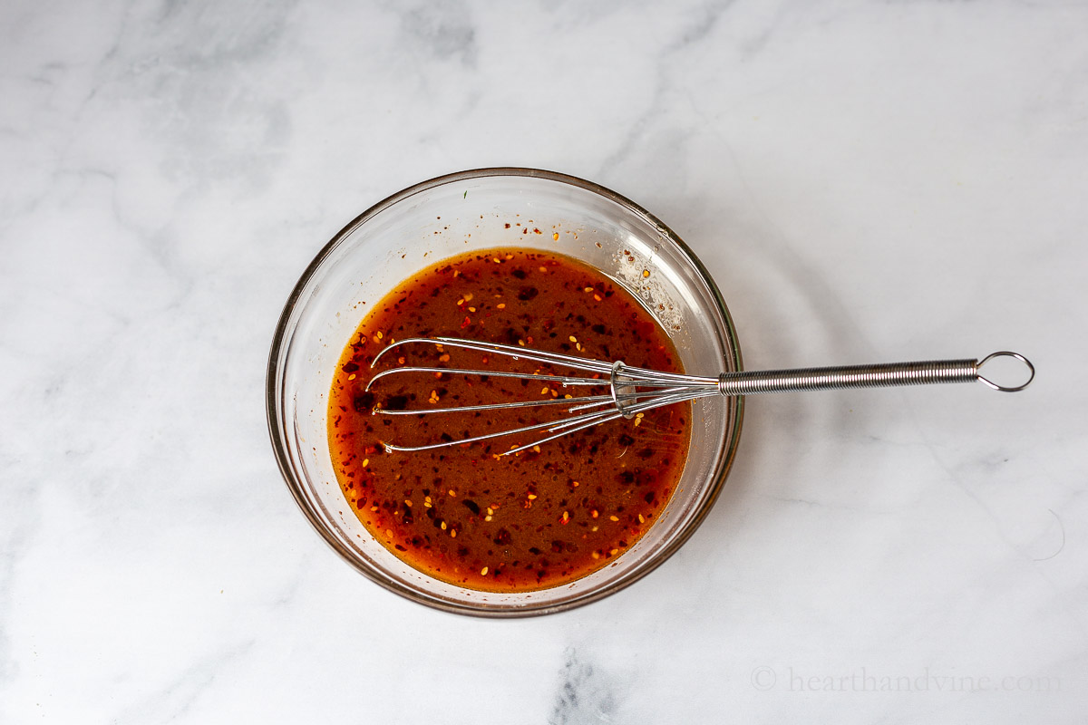 Beef and broccoli sauce in a bowl with a whisk.