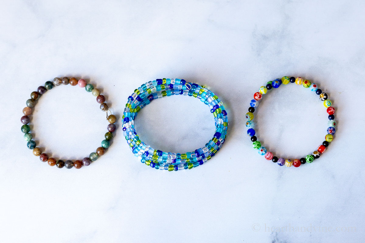 Three different memory wire bracelets on a table in a row.