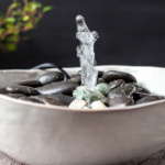 Water shooting out of the middle of a tabletop fountain made from a bowl.