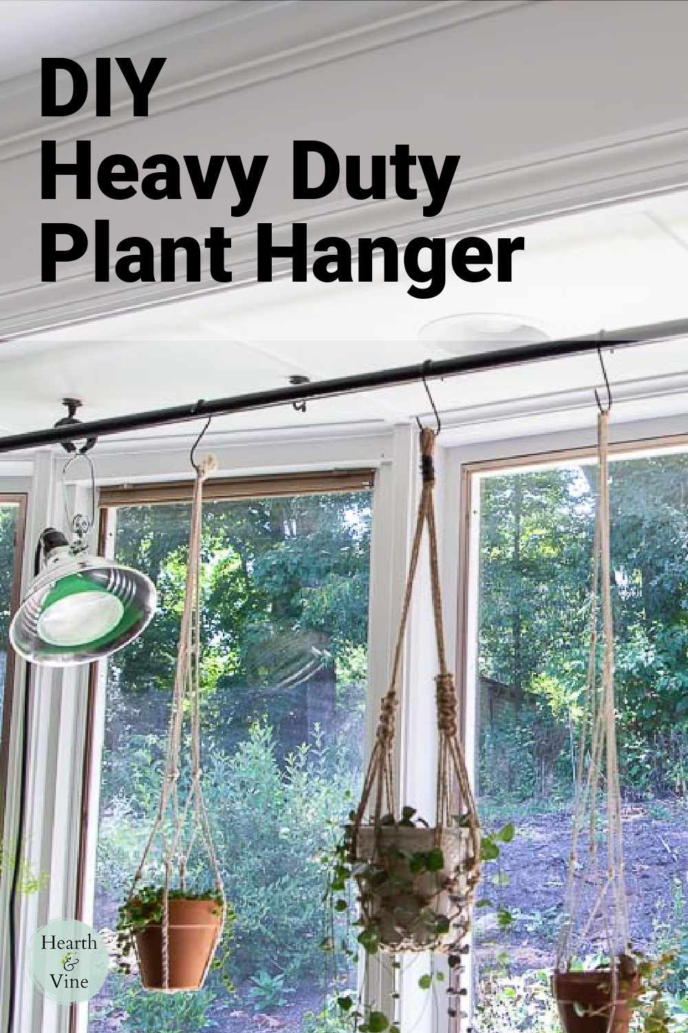 Bay window with long large industrial pipe plant hanger, plant lights and hanging plants.