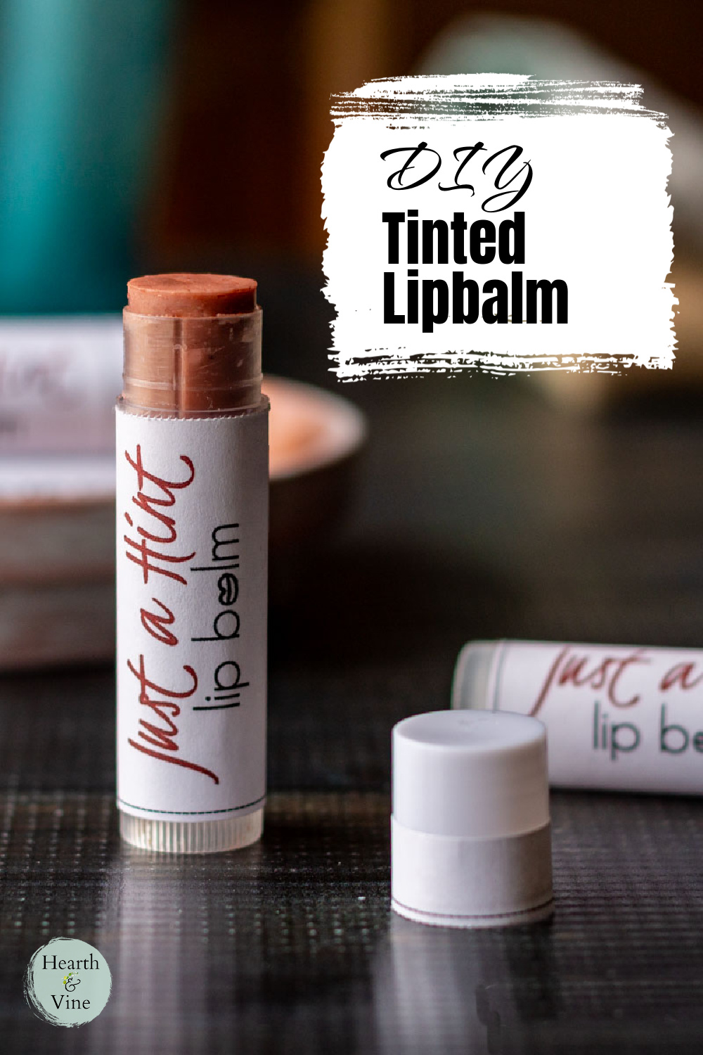 Tinted lip balm tube with the cap off standing up with a label saying Just a Hint.