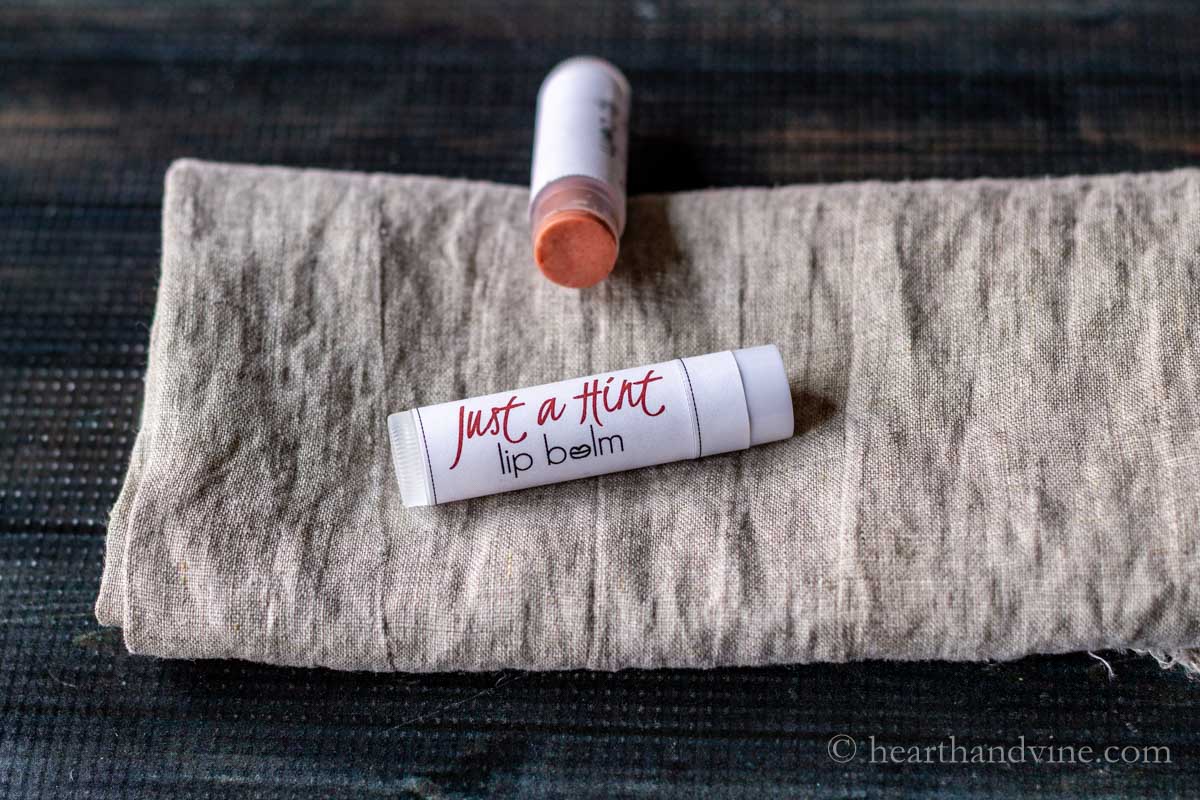 Two tubes of "Just a Hint" lip balm on a linen towel.