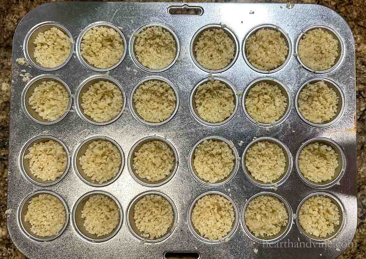 Breadcrumb mixture pressed into a mini muffin pan.