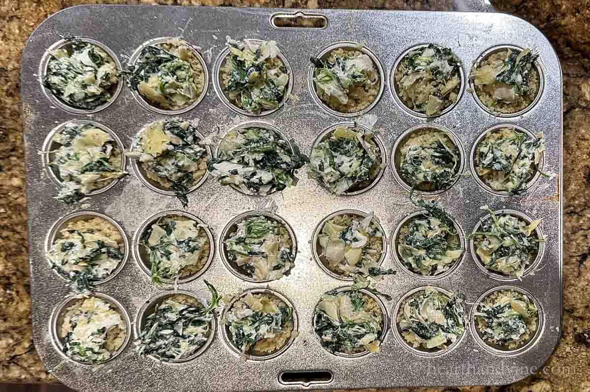 Spinach and artichoke dip portioned into the mini muffin sections.