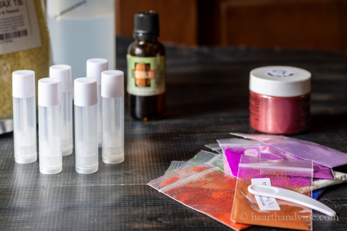 Supplies for tinted lip balm including mica powder, beeswax, coconut oil, empty lip balm tubes and geranium essential oil.