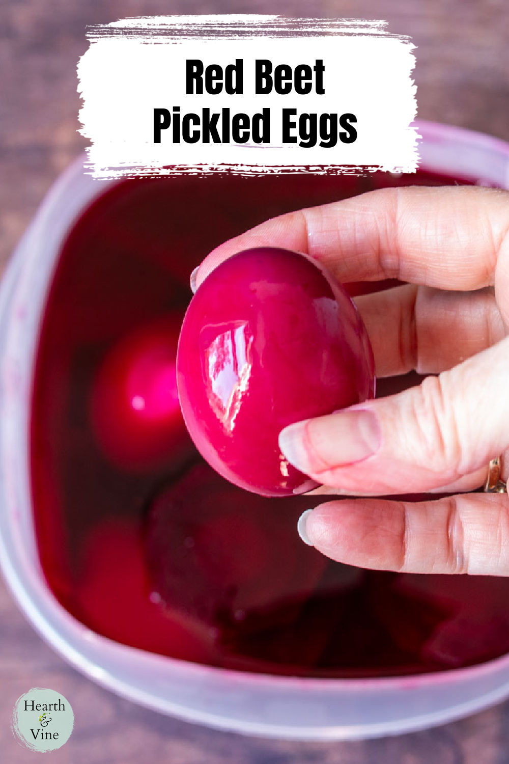 A hand holding a red beet pickled egg.
