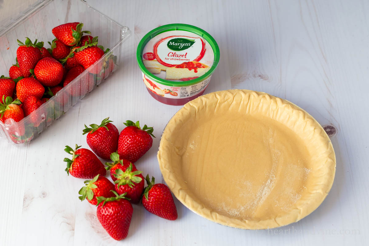 Ingredients for the strawberry glazed pie including a frozen pie shell, fresh strawberries and a container of strawberry glaze.