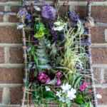 Pretty floral nature weaving with branches hanging on a brick wall.