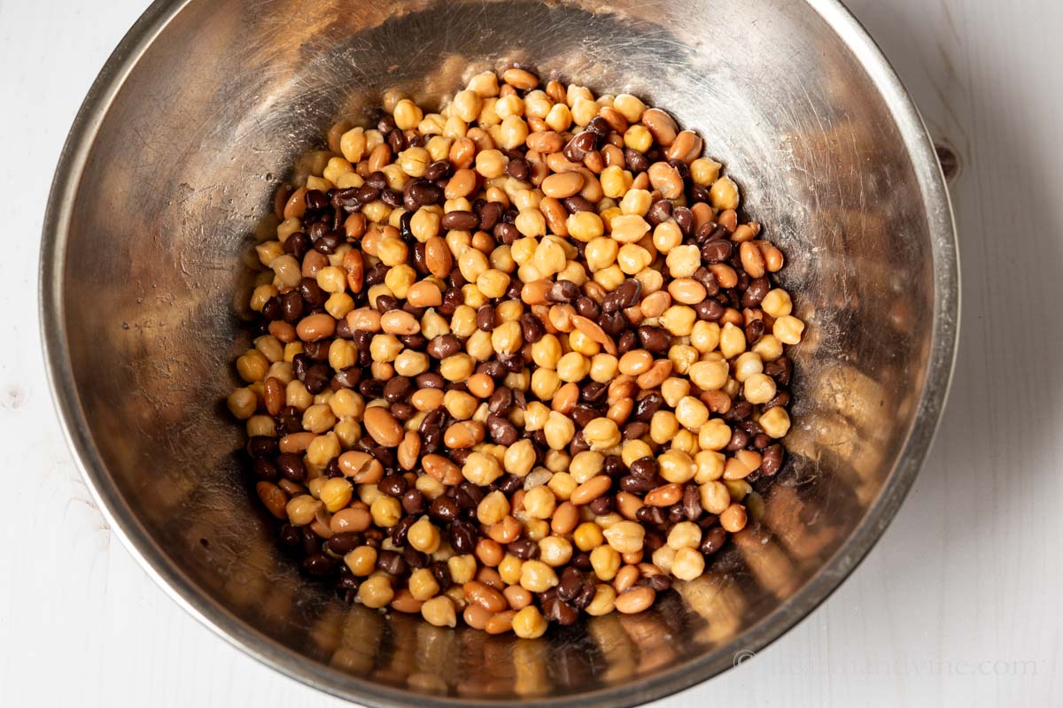 Chickpeas, black beans and pinto beans in a stainless steel mixing bowl.