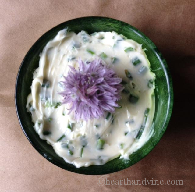 Bowl of chive butter with a chive blossom on top.