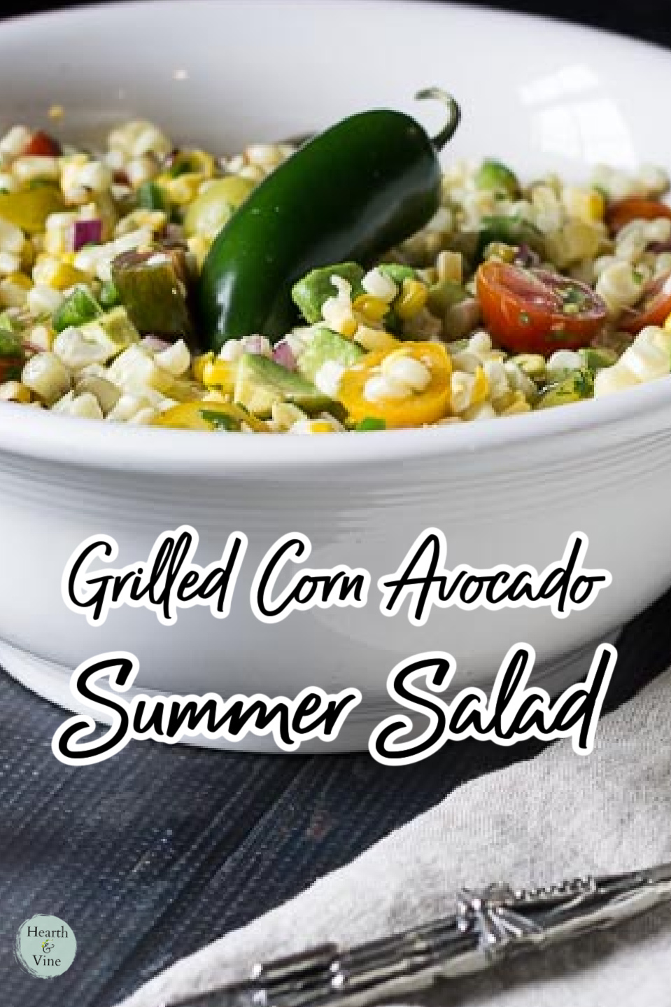 Large white serving bowl with grilled corn avocado salad and a fresh jalapeno pepper in the middle.