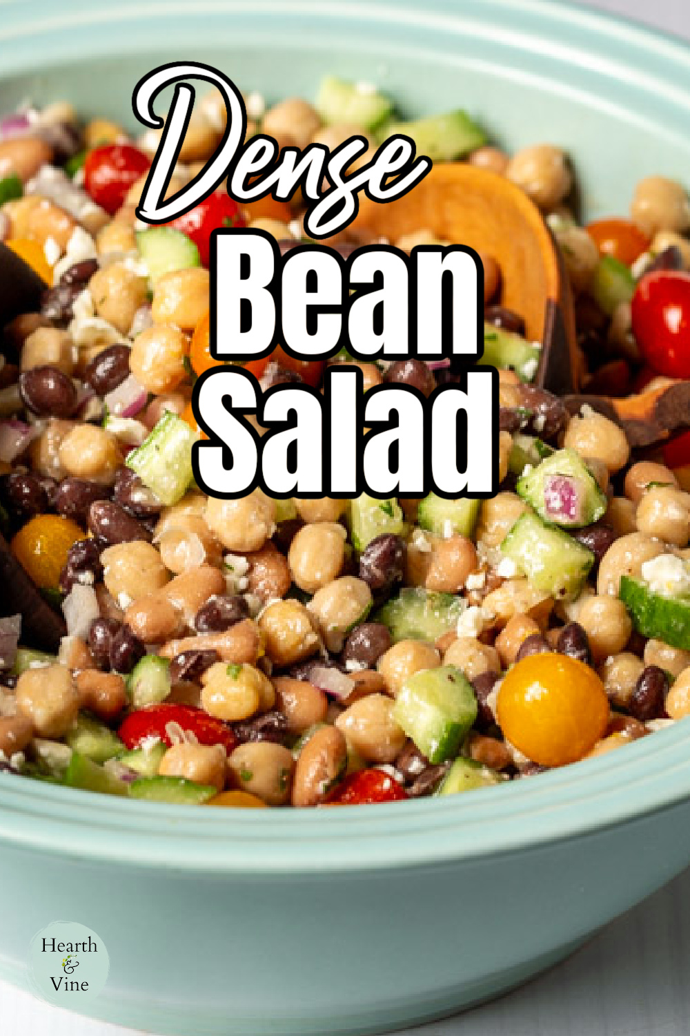 Close up view of the dense bean salad in a serving bowl with wooden serving utensils.