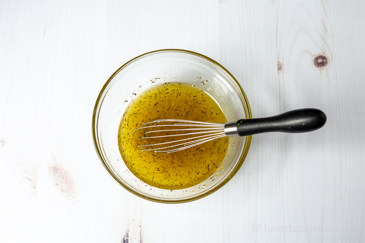 Citrus vinaigrette dressing in a clear bowl with a wire whisk.