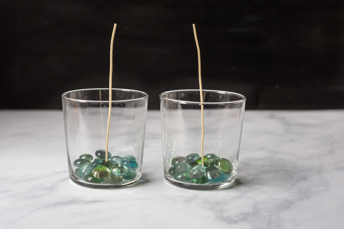 Two glasses with green and blue gems in the bottom and zinc wicks.