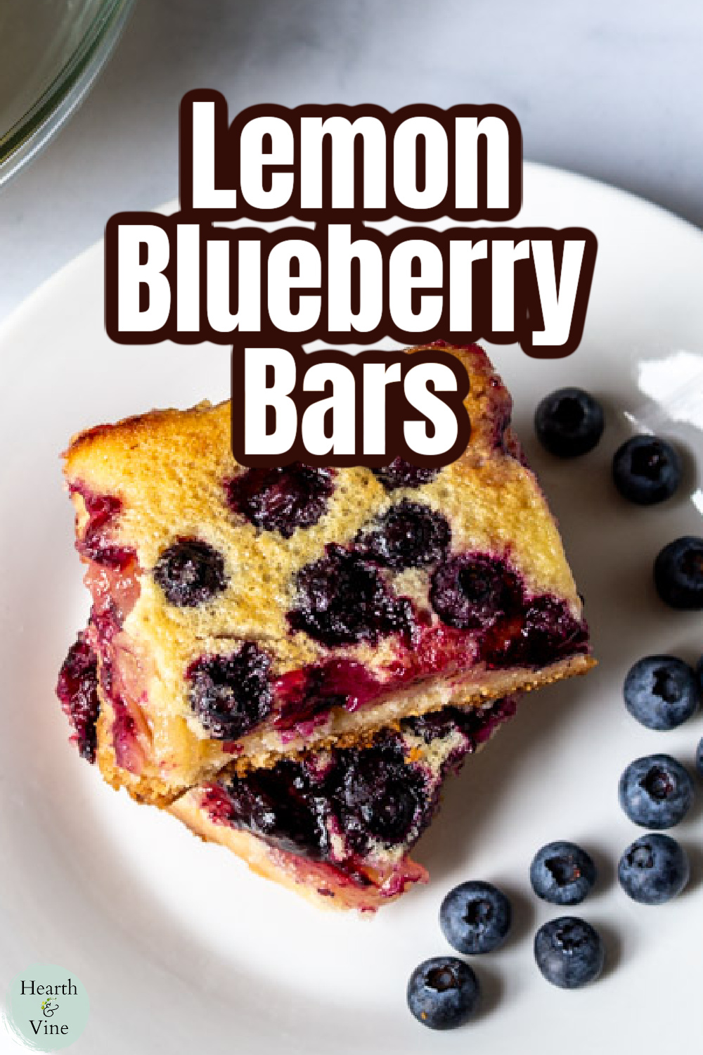 Aerial view of two stacked lemon blueberry bars with fresh blueberries on the side.