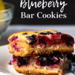 A close up look at two lemon blueberry bars stacked on top of each other on a white plate.
