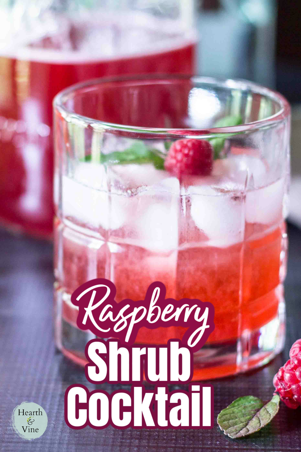 Cocktail glass with a raspberry shrub drink and a fresh berry on top.