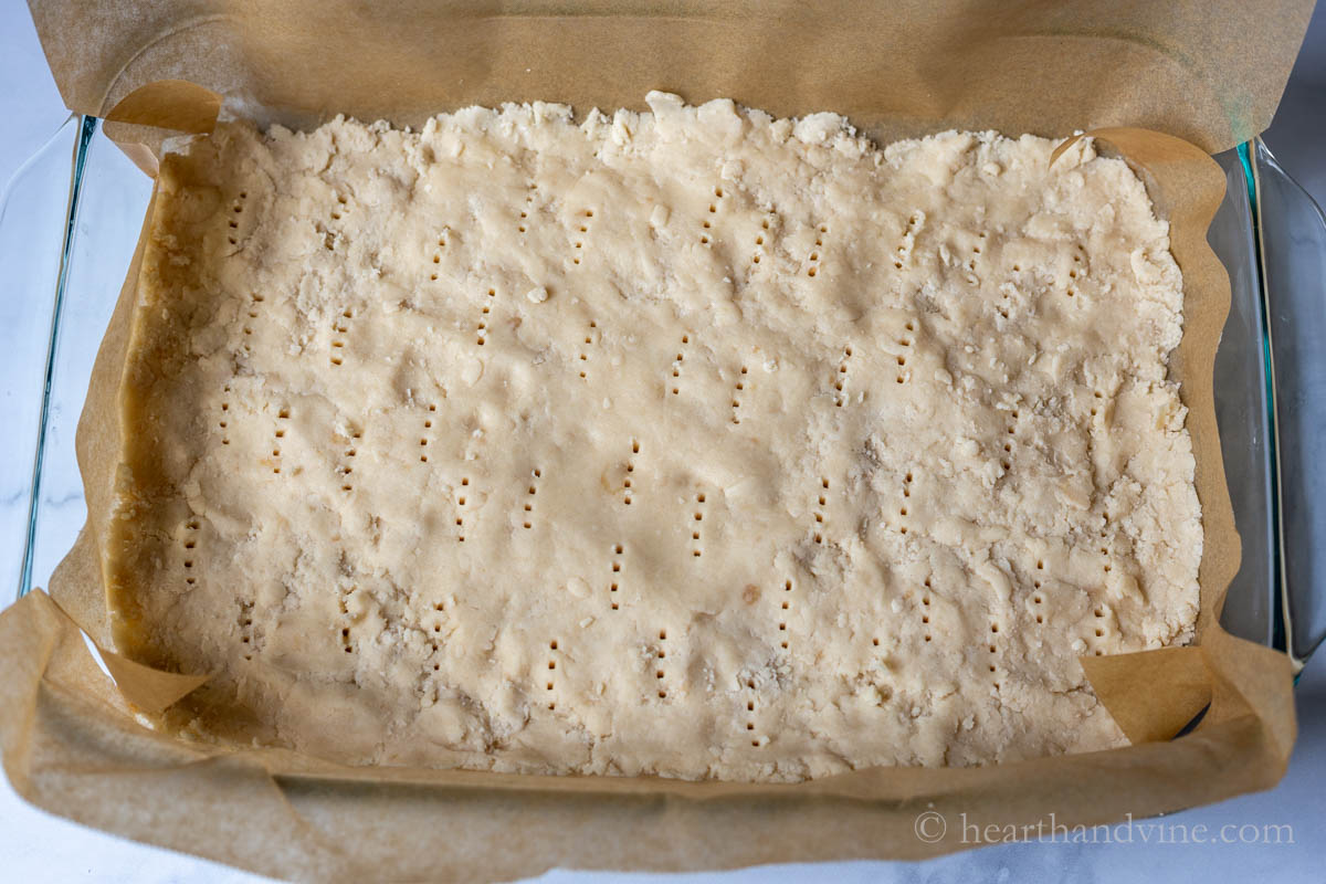 Shortbread crust pressed in a pan and fork marks all over.